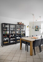 Black upholstered chairs at wooden table next to glass-fronted cabinets in dining room