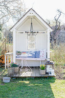 Romantische Kissen auf der Bank in der Gartenlaube mit kleiner Terrasse