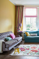 Gemütliche Sofas und Blumenteppich im Wohnzimmer mit gelber Wand