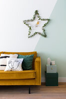 Star of eucalyptus twigs on two-tone wall above sofa