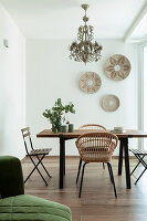 Dining table with various chairs and decorative wall plates in bright room