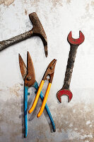 Hammer, tin snips and wrench on metal surface