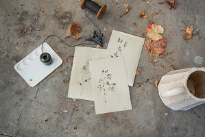 Handmade cards with drawings, paint and autumn leaves on concrete surface