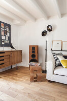 Weißes Sofa, Stehlampe, Lautsprecher, Retro Sideboard und Pinnwand in Loft-Wohnung