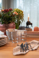 Besteck, Gläser, Geschirr und Blumenstrauß auf Esstisch