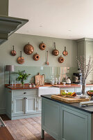 Kupfertöpfe an der Wand in hellgrüner, modernisierter Küche im Herrenhaus aus dem 18. Jahrhundert