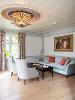 Silver-grey upholstered suite, mahogany table and gilded ceiling rosette in the living room