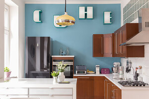 A breakfast counter in an open-plan kitchen with a light-blue wall