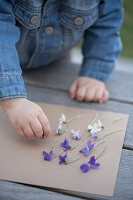 Mädchen spielt mit Veilchenblüten