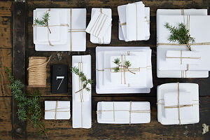 Weiß verpackte Geschenke als Adventskalender mit Wacholderwzeigen dekoriert