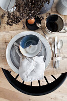 Place setting with ceramic dishes and linen napkin on Easter breakfast table