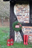 Red Hunter wellingtons and lanterns outside half-timbered house with old-fashioned Christmas wreath