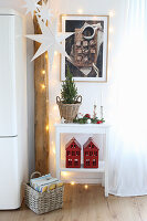 Christmas decorations in the kitchen: wooden beam with fairy lights, paper star and house-shaped candle lanterns