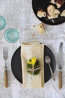 Moss egg with daffodil on a napkin in a rustic table setting
