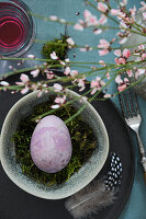 Purple Easter egg on a bed of moss in a bowl