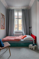 Bett mit Bettkasten im Zimmer mit bodenlangem Vorhang und Stuckleiste