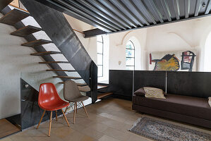 Lounge with classic chairs, daybed and metal staircase in converted church