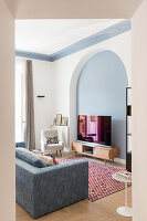 Sofa, armchairs, and TV furniture in renovated living room with round-arched wall niche