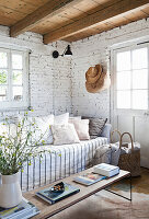 Sofa with cushions and coffee table in room with whitewashed brick wall