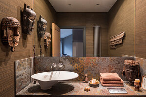African masks and Brazilian slate in cloakroom with walls bedecked in Foja grass cloth from Brian Yates