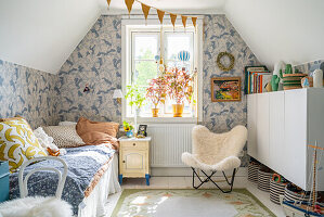 Bett, Sessel und Wandschrank im Jungenzimmer mit blau-weißer Tapete