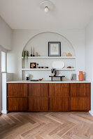 Fitted sideboard below shelves in arched niche