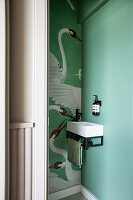 Mini bathroom with small sink and bird wallpaper in mint green
