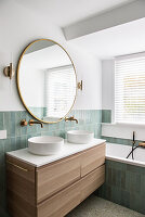 Large round mirror above twin round countertop basins in bathroom