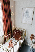 Boy's bedroom with cot, fairy lights and terracotta accents