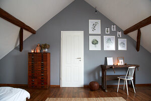 Work area in the attic with dark wooden furniture and plant illustrations on the wall