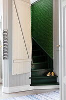 Treppenhaus mit schmalen grünen Treppen und grüner Tapete