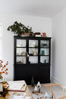 Black display cabinet with glass front in the living room, festively decorated