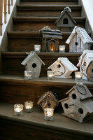 Birdhouses and tea lights decorated on wooden steps