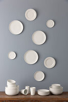 Pile of dishes and white plates on grey wall