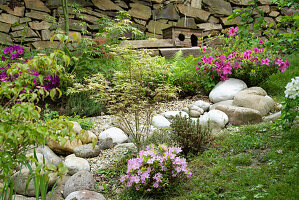 Üppig bewachsener Sommergarten mit Natursteinen und Trockensteinmauer