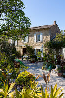 Blick auf provenzalisches Landhaus mit weißen Fensterläden, Terrasse und Garten