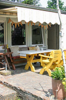 Gelb lackierter Holztisch mit Stühlen und Bank auf der Terrasse