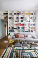 Raumhohes Bücherregal und Sofa im Wohnzimmer, Couchtisch und Beistelltisch mit Büchern