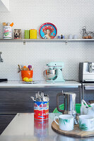 Blick über Esstisch auf Küchenzeile und Regal vor gefliester Wand
