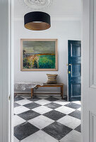 Elegant hall with chequered marble floor, wooden bench and artwork
