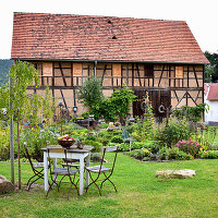 Seating area in rustic garden in front of half-timbered barn