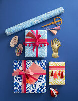 Wrapped gifts decorated with pompom trim and tassels, roll of wallpaper and decorative objects