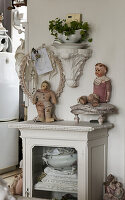 Old dolls on glass cabinet with table linen and tableware