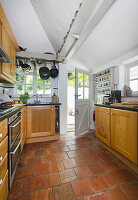 Kitchen with terracotta tiles, wooden cupboards and spice rack