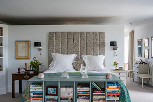 Bett mit gemustertem Kopfteil und mintfarbenem Bücherregal im hellen Schlafzimmer