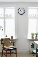 Wooden chair with fur throw in front of window sill with potted plants