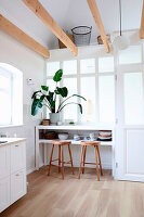 Bright dining area under window, bar stools and houseplant