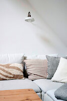 White corner sofa with throw pillows and wall lamp in a minimalist style