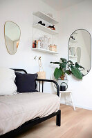 Couch with metal frame, white wall shelves and oval mirrors