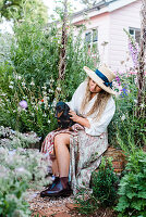 Woman with dachshund on her lap in flower garden